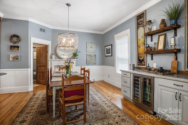 420 S Cedar St, Lincolnton, NC 28092 - dining room with wine cooler, light wood-style flooring, bar, a wainscoted wall, and crown molding