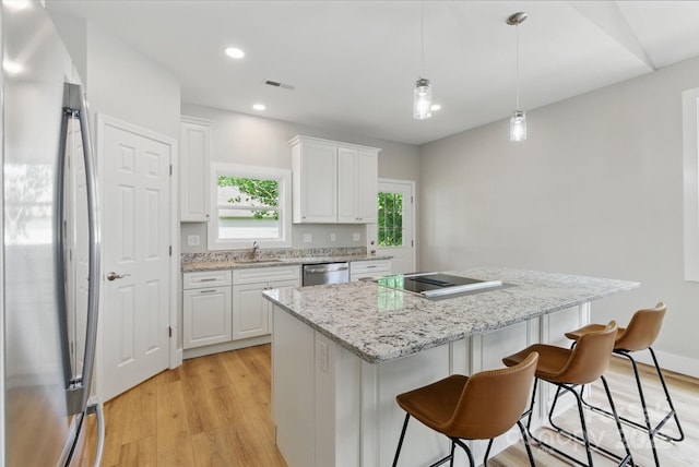 192 Plato Pl, Etowah, NC 28729 - kitchen with stainless steel appliances, a kitchen island, white cabinetry, light wood finished floors, and a sink