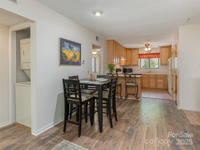 55 Lake Dr Unit 4P, Laurel Park, NC 28739 - dining room featuring estacked washer and dryer, light wood-style floors, a ceiling fan, and baseboards