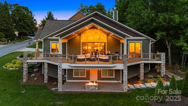 15 Ledgestone Dr, Fairview, NC 28730 - back of house at dusk featuring a patio, an outdoor fire pit, a yard, and a chimney
