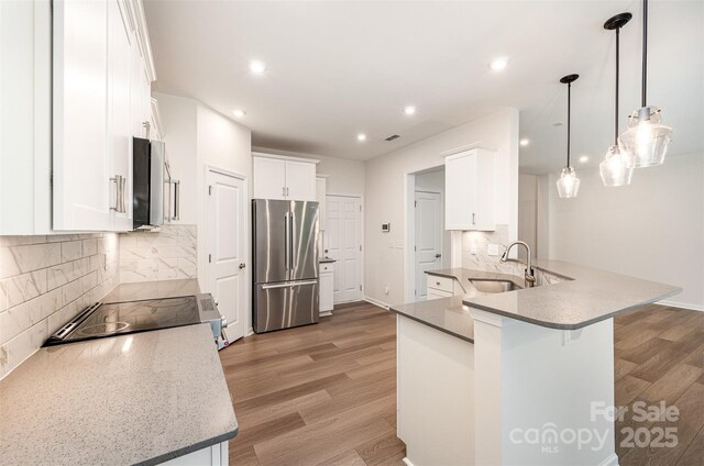 9009 Odell Corners Blvd NW, Concord, NC 28027 - kitchen with stainless steel appliances, a sink, light wood-style flooring, decorative backsplash, and recessed lighting