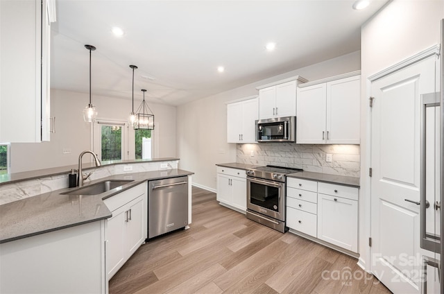 9009 Odell Corners Blvd NW, Concord, NC 28027 - kitchen featuring appliances with stainless steel finishes, a sink, white cabinetry, light wood finished floors, and tasteful backsplash