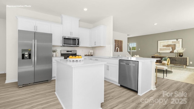 3734 Coleman Dr, Charlotte, NC 28215 - kitchen with stainless steel appliances, light wood-style flooring, a sink, light countertops, and a peninsula