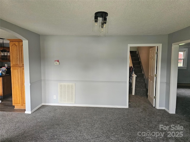 905 Klondale St, China Grove, NC 28023 - unfurnished dining area featuring dark carpet, a textured ceiling, arched walkways, stairs, and baseboards