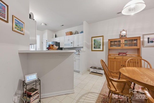 12350 Swan Wings Pl, Huntersville, NC 28078 - kitchen featuring white microwave, light tile patterned flooring, freestanding refrigerator, light countertops, and white cabinets