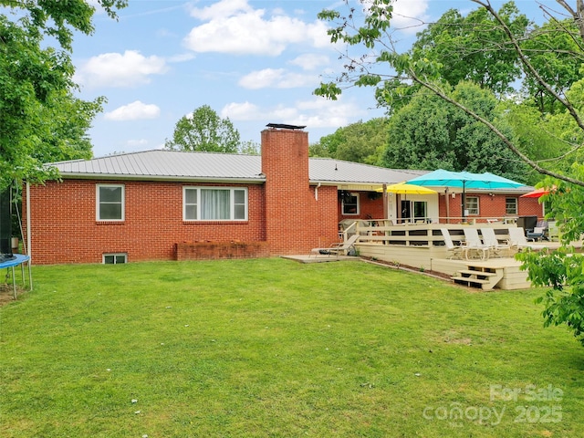 391 Ellen Ave, Canton, NC 28716 - back of house featuring a trampoline, a deck, brick siding, a chimney, and metal roof