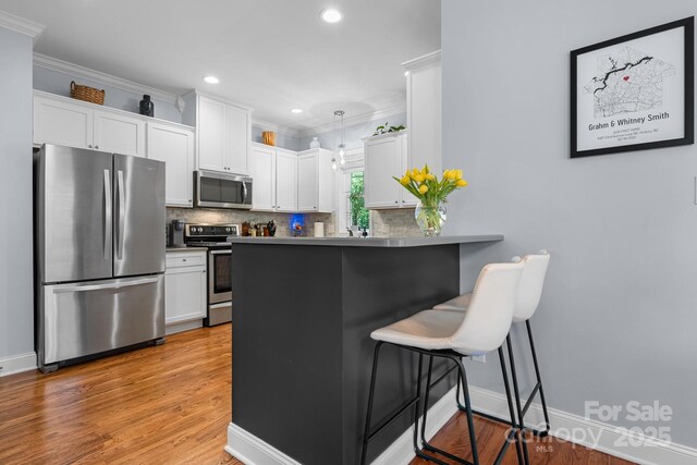 1067 33rd Avenue Loop NE, Hickory, NC 28601 - kitchen with stainless steel appliances, a breakfast bar, white cabinetry, backsplash, and crown molding
