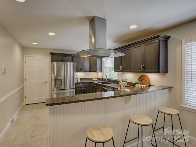 6116 Springhouse Ln, Charlotte, NC 28211 - kitchen with stainless steel fridge with ice dispenser, island exhaust hood, dark brown cabinetry, dark stone counters, and a peninsula