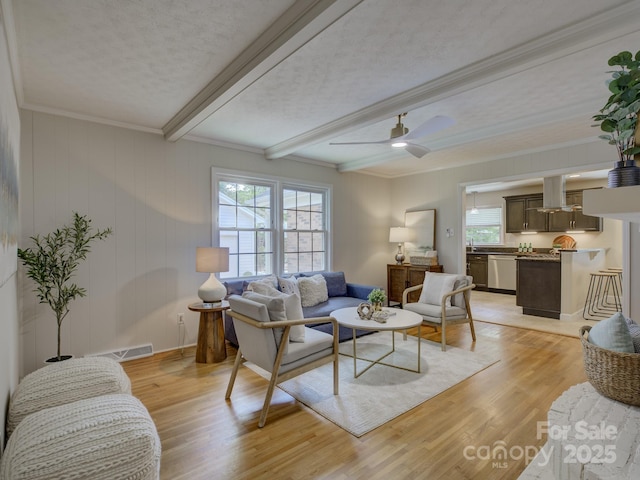 6116 Springhouse Ln, Charlotte, NC 28211 - living room with beamed ceiling, light wood-type flooring, ornamental molding, a textured ceiling, and a ceiling fan