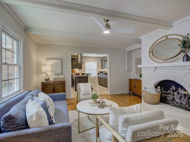 6116 Springhouse Ln, Charlotte, NC 28211 - living area featuring light wood-style floors, ornamental molding, a ceiling fan, beam ceiling, and a brick fireplace