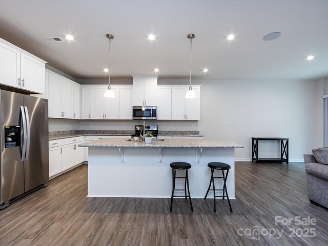 403 Park Meadows Dr, Matthews, NC 28104 - kitchen with appliances with stainless steel finishes, dark wood-style floors, a breakfast bar, a center island with sink, and recessed lighting