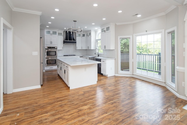 6400 Morningsong Ln, Charlotte, NC 28269 - kitchen featuring extractor fan, a chandelier, crown molding, light wood finished floors, and decorative backsplash