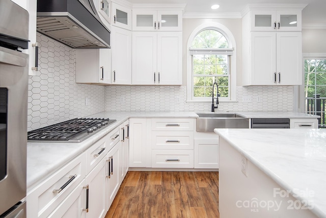 6400 Morningsong Ln, Charlotte, NC 28269 - kitchen with wall chimney exhaust hood, stainless steel gas cooktop, crown molding, wood finished floors, and white cabinetry