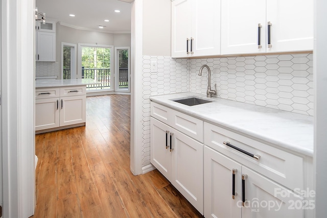 6400 Morningsong Ln, Charlotte, NC 28269 - kitchen with ornamental molding, white cabinets, light wood finished floors, backsplash, and recessed lighting