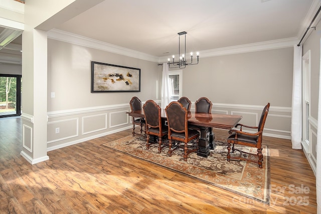 6400 Morningsong Ln, Charlotte, NC 28269 - dining area featuring crown molding, a chandelier, wood finished floors, wainscoting, and a decorative wall