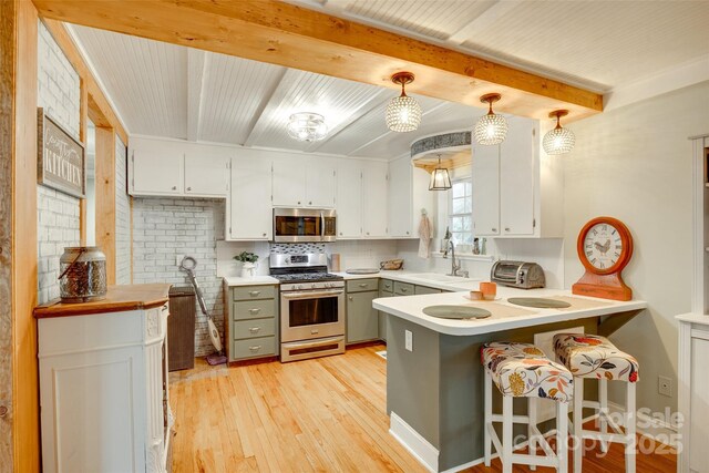 504 Amon Ln, Pineville, NC 28134 - kitchen with appliances with stainless steel finishes, a sink, light wood finished floors, a peninsula, and light countertops