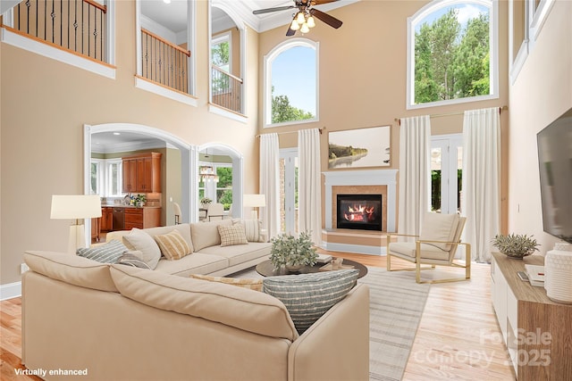 3204 Mcpherson St, Waxhaw, NC 28173 - living room with ornamental molding, ceiling fan, a glass covered fireplace, plenty of natural light, and light wood-type flooring