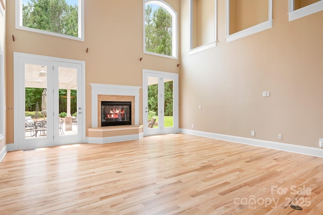 3204 Mcpherson St, Waxhaw, NC 28173 - unfurnished living room featuring a high ceiling, a glass covered fireplace, light wood-type flooring, and baseboards