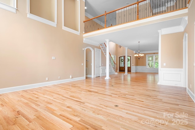 3204 Mcpherson St, Waxhaw, NC 28173 - unfurnished living room with a chandelier, a towering ceiling, crown molding, light wood-style floors, and stairway