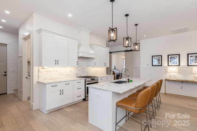 40 Hidden Pond Ln, Brevard, NC 28712 - kitchen with gas stove, a sink, light wood-style floors, custom range hood, and recessed lighting