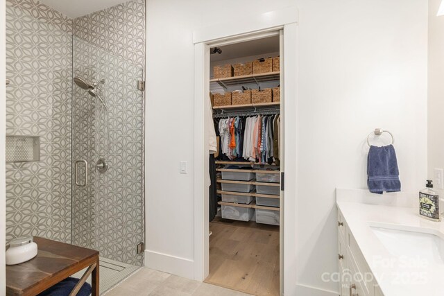 40 Hidden Pond Ln, Brevard, NC 28712 - bathroom with vanity, a stall shower, wood finished floors, a spacious closet, and baseboards