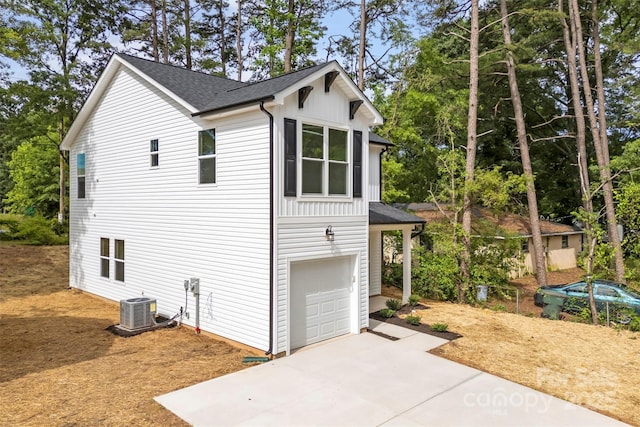 105 Spring Garden Dr, Gastonia, NC 28052 - view of property exterior featuring a garage, central air condition unit, concrete driveway, roof with shingles, and view of wooded area
