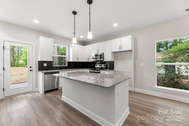 105 Spring Garden Dr, Gastonia, NC 28052 - kitchen featuring appliances with stainless steel finishes, tasteful backsplash, light stone counters, a center island, and light wood-style floors