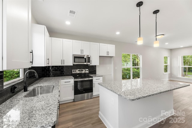 105 Spring Garden Dr, Gastonia, NC 28052 - kitchen with stainless steel appliances, a sink, decorative backsplash, white cabinetry, and a kitchen island
