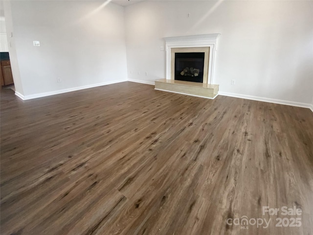 204 W Boyd St, Maiden, NC 28650 - unfurnished living room with dark wood-style flooring, a fireplace with raised hearth, and baseboards