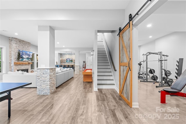 2289 Pine Valley Dr, Denver, NC 28037 - stairs with a barn door, wood finished floors, a stone fireplace, recessed lighting, and baseboards