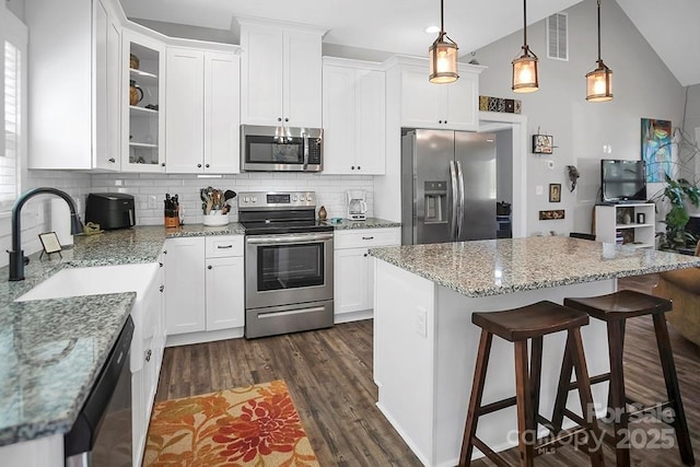 5016 Old Pine Ln, Cherryville, NC 28021 - kitchen with stainless steel appliances, a breakfast bar area, decorative backsplash, white cabinets, and lofted ceiling