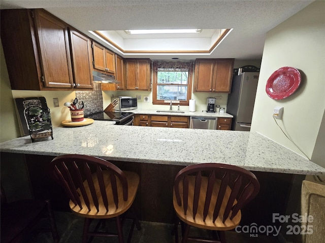 105 Bent Creek Blvd Unit 16, Lake Lure, NC 28746 - kitchen with appliances with stainless steel finishes, a peninsula, under cabinet range hood, a sink, and a kitchen breakfast bar