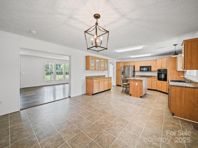 714 Helms Efird Rd, Marshville, NC 28103 - kitchen with black appliances, a textured ceiling, a kitchen island, light tile patterned flooring, and hanging light fixtures