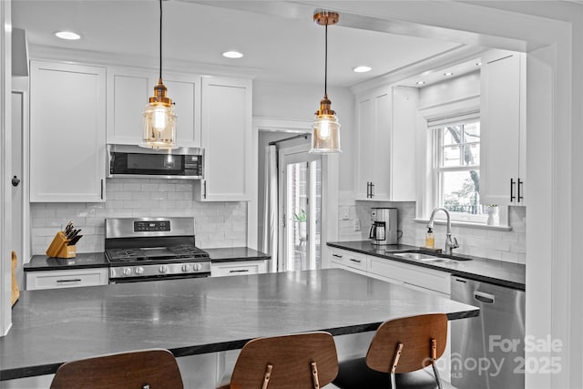 1729 Kensington Dr, Charlotte, NC 28205 - kitchen with stainless steel appliances, dark countertops, a sink, a breakfast bar, and white cabinets