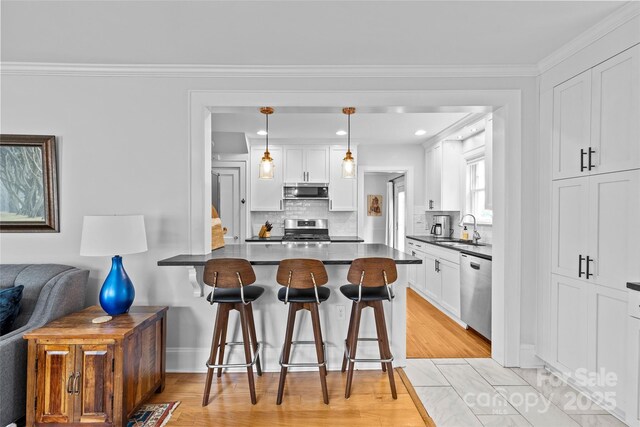 1729 Kensington Dr, Charlotte, NC 28205 - kitchen featuring stainless steel appliances, a sink, a kitchen bar, dark countertops, and white cabinetry