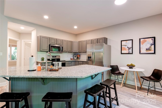 145 Inn At Crestwood Dr, Boone, NC 28607 - kitchen with gray cabinets, stainless steel appliances, light wood-style floors, a kitchen breakfast bar, and baseboards
