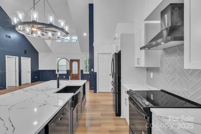 1246 Bob Falls Rd, Shelby, NC 28150 - kitchen with wall chimney exhaust hood, black appliances, high vaulted ceiling, white cabinetry, and light wood-style flooring
