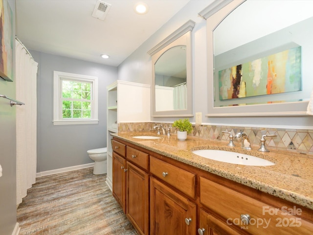 7356 Terrace Dr, Charlotte, NC 28211 - bathroom featuring double vanity, toilet, baseboards, wood finished floors, and decorative backsplash