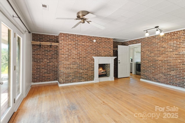 103 Hampshire Ln, Canton, NC 28716 - unfurnished living room featuring brick wall, wood-type flooring, a ceiling fan, a fireplace, and baseboards