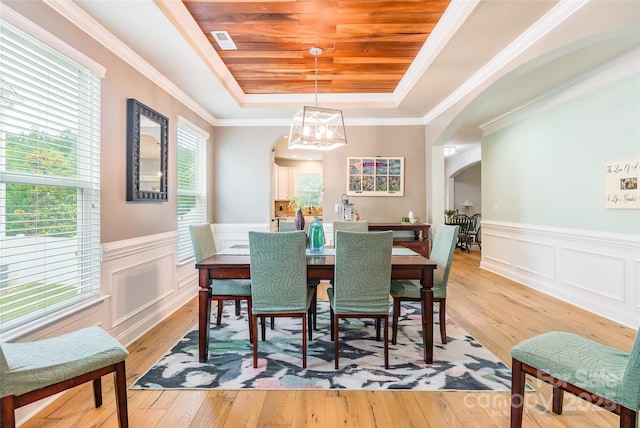 85017 Newloch Ct, Lancaster, SC 29720 - dining room featuring a tray ceiling, arched walkways, light wood finished floors, a chandelier, and wainscoting