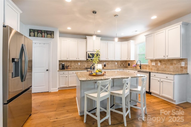 85017 Newloch Ct, Lancaster, SC 29720 - kitchen with appliances with stainless steel finishes, a sink, white cabinets, a center island, and light wood-type flooring