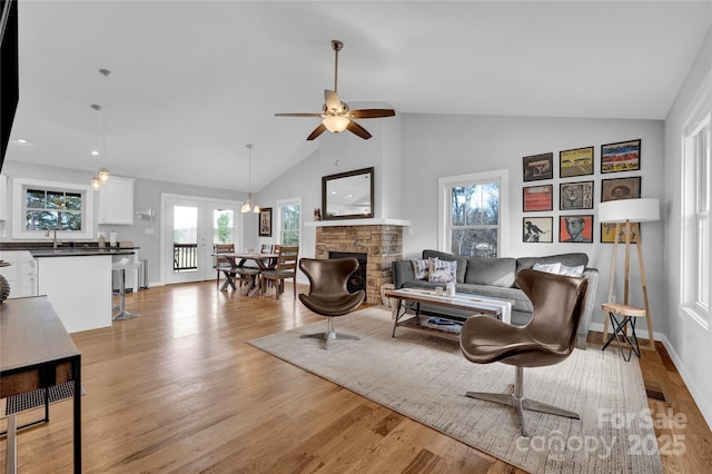 11 Ridge Brook Dr, Weaverville, NC 28787 - living area featuring light wood finished floors, a ceiling fan, high vaulted ceiling, a stone fireplace, and baseboards
