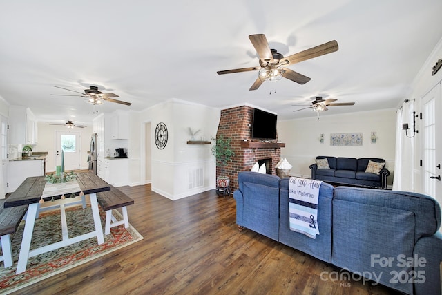 2248 White Heron Rd, Liberty Hill, SC 29074 - living area featuring ceiling fan, dark wood-type flooring, a brick fireplace, and crown molding