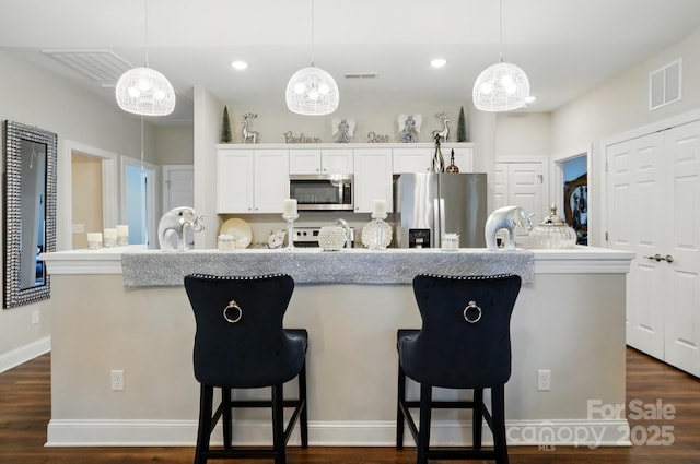 204 Craig St, Mount Holly, NC 28120 - kitchen with appliances with stainless steel finishes, a kitchen bar, an island with sink, white cabinetry, and dark wood-style floors