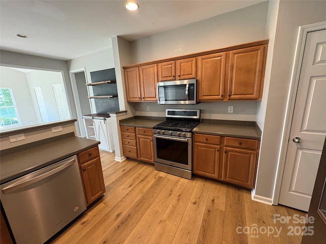 2567 Holly Oak Ln, Gastonia, NC 28056 - kitchen with stainless steel appliances, dark countertops, light wood-type flooring, brown cabinets, and recessed lighting