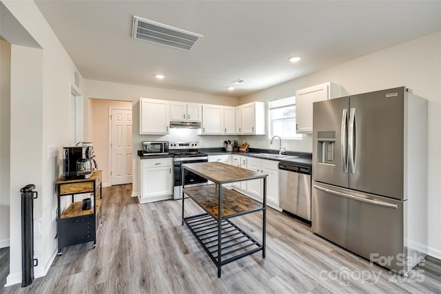 415 Kickapoo Ave, Gastonia, NC 28056 - kitchen featuring stainless steel appliances, dark countertops, a sink, light wood-style flooring, and recessed lighting