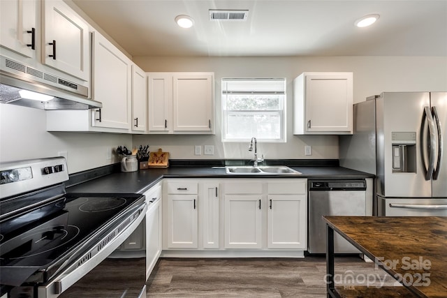 415 Kickapoo Ave, Gastonia, NC 28056 - kitchen featuring stainless steel appliances, a sink, under cabinet range hood, dark countertops, and dark wood-type flooring
