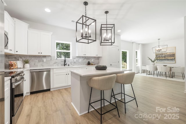 2313 Stallings Rd, Harrisburg, NC 28075 - kitchen featuring stainless steel appliances, a chandelier, a sink, a kitchen island, and light wood-style flooring