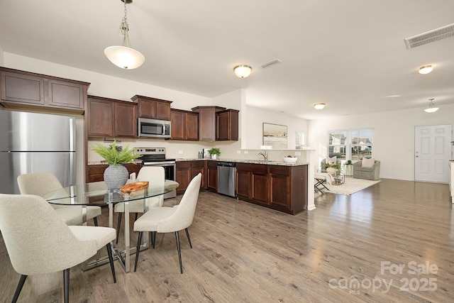 5160 Thomasville Dr Unit 123, Belmont, NC 28012 - kitchen with stainless steel appliances, dark brown cabinets, light wood-style flooring, a peninsula, and a sink