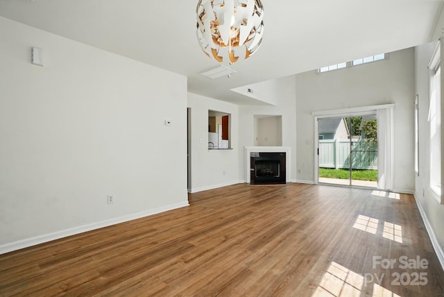 8605 Sawleaf Ct, Charlotte, NC 28215 - unfurnished living room with a chandelier, baseboards, wood finished floors, and a fireplace with flush hearth